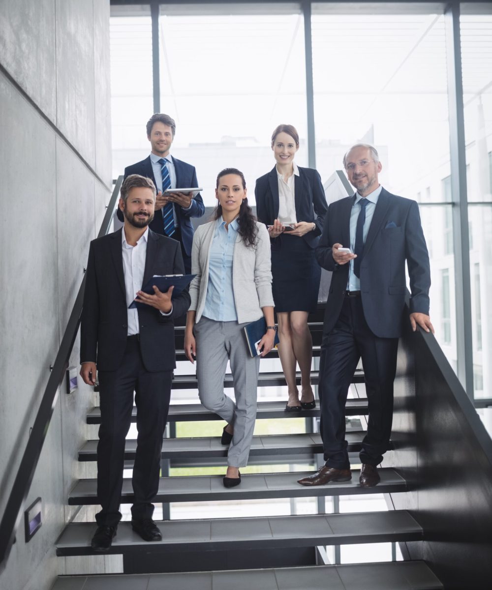 Portrait of confident businesspeople standing on staircase in office